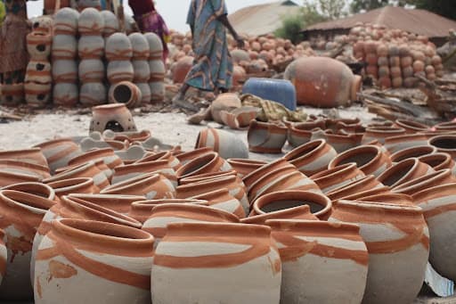Rows of hand-thrown clay pots dry in an open-air pottery market.