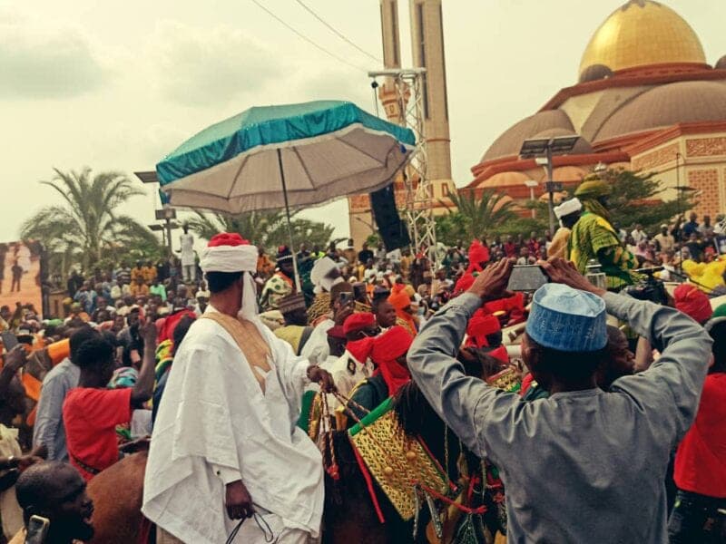 Crowds and horsemen gather outside the domed Ilorin Central Mosque during the Durbar celebration.