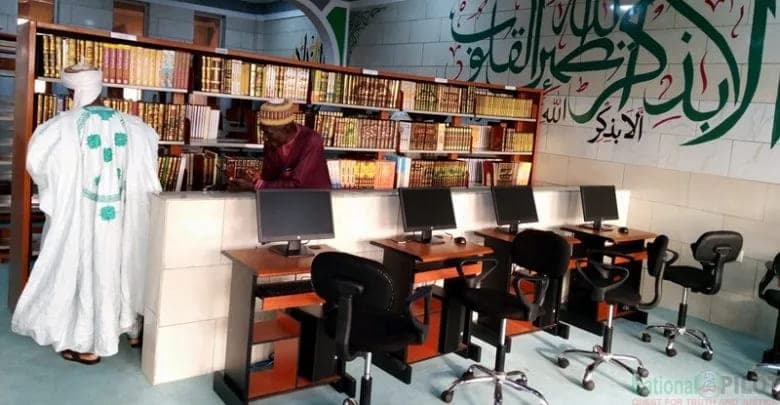 A reading room lined with bound volumes and Arabic calligraphy, where writers and researchers work.
