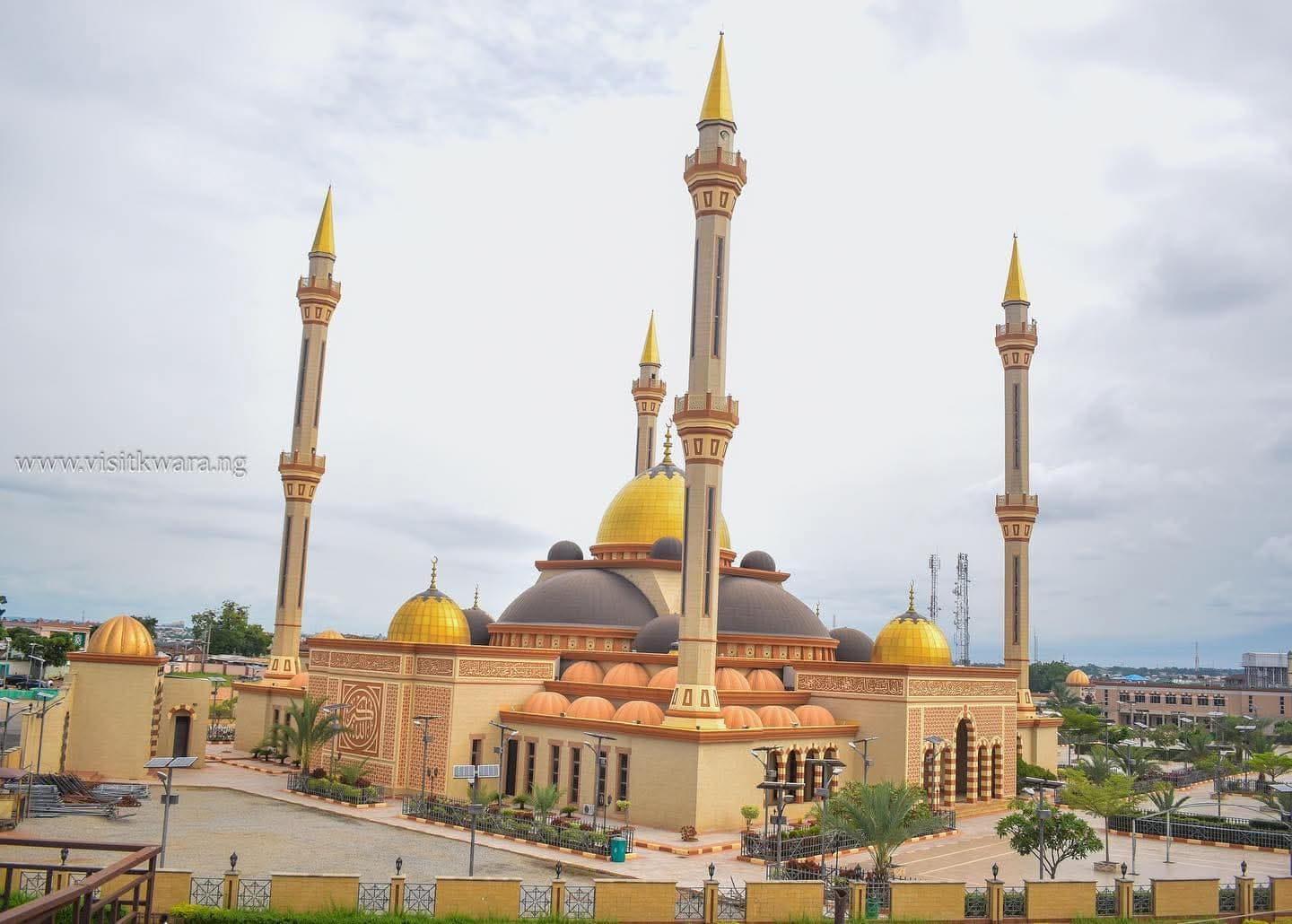 The gold-domed minarets of Ilorin Central Mosque rise into an overcast sky above the surrounding city.